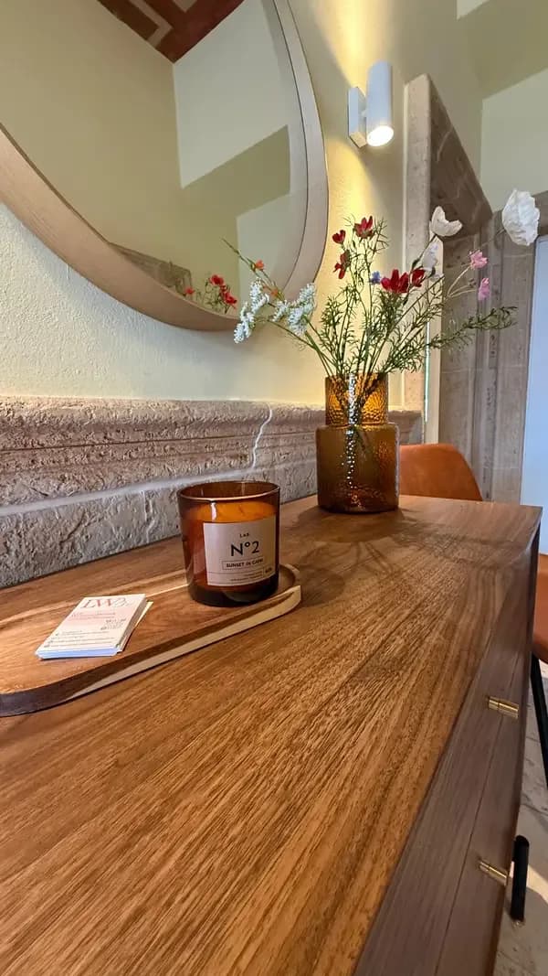 Holztresen mit Duftkerze, Visitenkarten und frischen Blumen